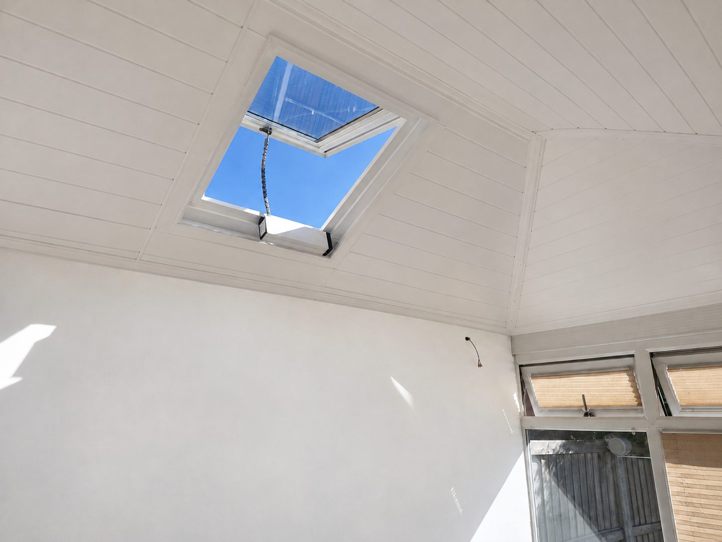 Finished insulated ceiling in Luton with the new plasterboarded wall on the side facing the fence